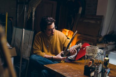 Adam atölyesinde ahşapla çalışıyor.