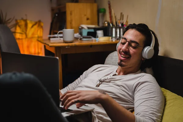 Молодий Чоловік Використовує Ноутбук Сидячи Своїй Кімнаті Він Носить Навушники — стокове фото