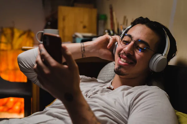 Homem Com Fones Ouvido Usando Smartphone Enquanto Deitado Sofá Seu — Fotografia de Stock