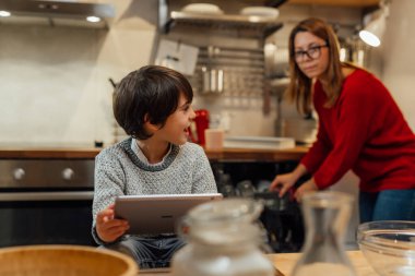Anne ve çocuk mutfaktaki dijital tablette yemek tarifi arıyorlar.
