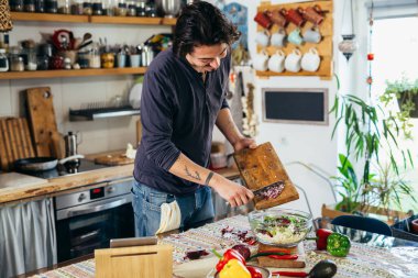 Adam evde sebze salatası hazırlıyor.