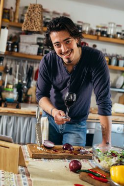 Adam evde sebze salatası hazırlıyor. Kameraya bakıyor.