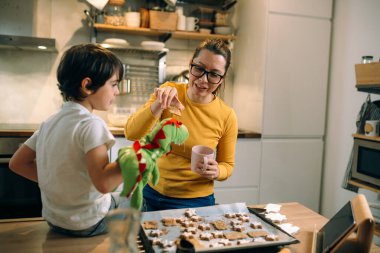 Anne ve oğlu mutfakta yemek hazırlarken eğleniyorlar.