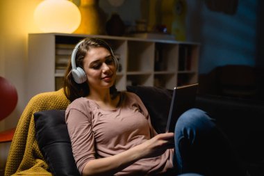 Kadın evde dijital tablet kullanıyor ve müzik dinliyor