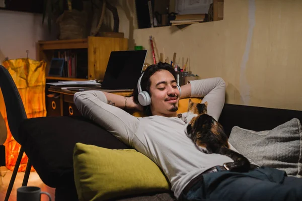 Чоловік Розслабляється Своєю Кішкою Слухаючи Музику Навушниках Вдома — стокове фото