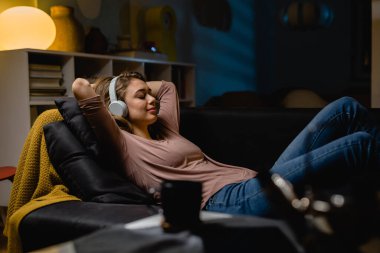 Kadın evde dinleniyor, müzik dinliyor.