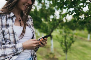 Kadın çiftçi meyve bahçesinde akıllı telefon kullanıyor.