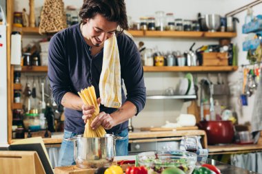 Adam mutfakta yemek pişiriyor.