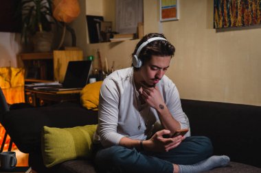 Adam odasında akıllı telefon kullanıyor.
