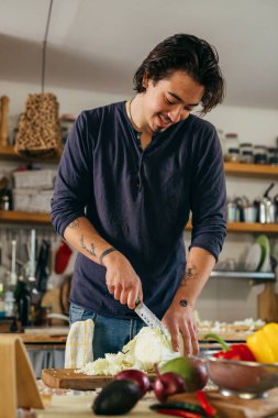 Adam mutfağında lahana kesiyor.