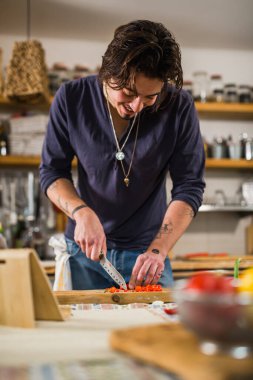 Adam mutfakta kırmızı biber kesiyor.