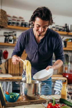 Adam evde spagetti hazırlıyor.