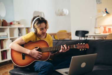 Genç evde gitar çalıyor..