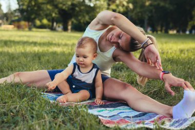 Anne ve oğlu halka açık parkta fiziksel egzersiz yapıyorlar.