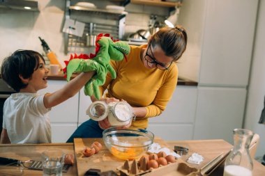 Anne ve oğlu mutfakta birlikte yemek pişiriyorlar.