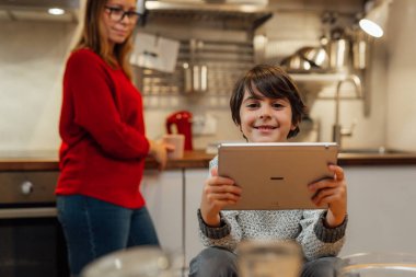 Küçük çocuk mutfakta dijital tablet kullanıyor.