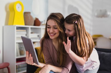 Anne ve kızı çevrimiçi görüntülü sohbet için dijital tablet kullanıyor