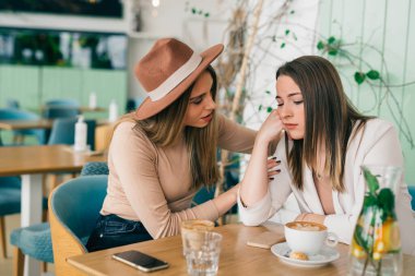 Kadınlar kafeteryada arkadaşlarını rahatlatır.