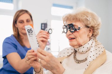 senior woman has eyesight examination in clinic clipart