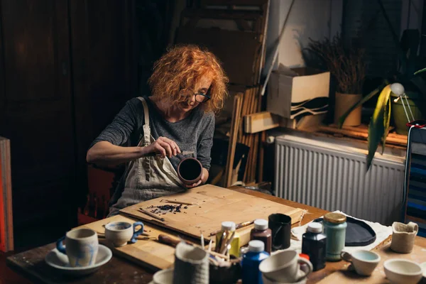 Atölyesinde kilden tencere oyan bir kadın.