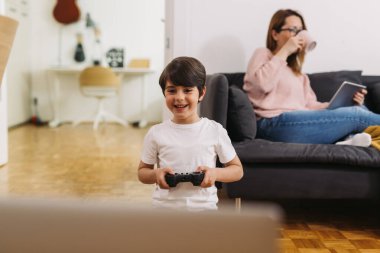 Anne ve oğlu evde video oyunu oynuyorlar.