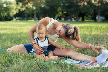 Anne ve çocuğu halka açık parkta fiziksel egzersizler yapıyorlar.
