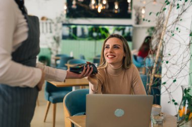 Kadın kafeteryada kartla ödeme yapıyor.