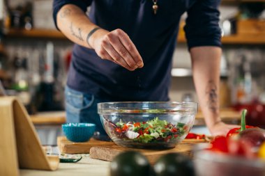 Adam mutfağında salata pişiriyor.