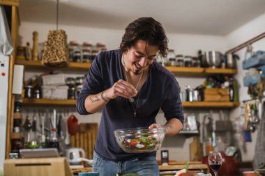 Adam mutfağında salata pişiriyor.