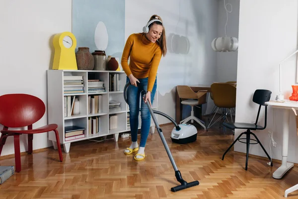 woman vacuuming at home and listening music