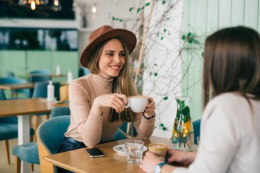 Kadın kafede konuşuyor ve kahve içiyor.