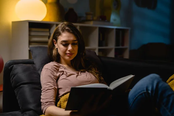 Mujer Relajándose Sofá Usando Libro Lectura Casa — Foto de Stock