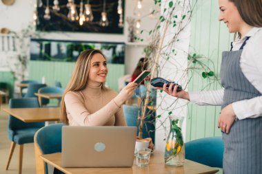 Kafe 'de akıllı telefondan para ödeyen bir kadın.