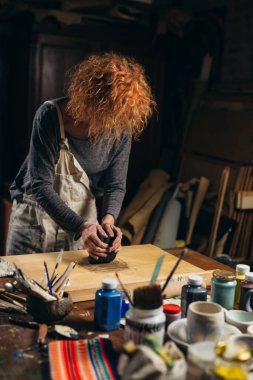 Kadın atölyesinde çömlek yapıyor.