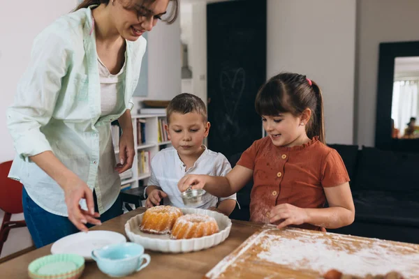 mother and kids preparing sweet cakes at home