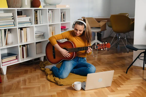 Kadın evde gitar çalıyor.