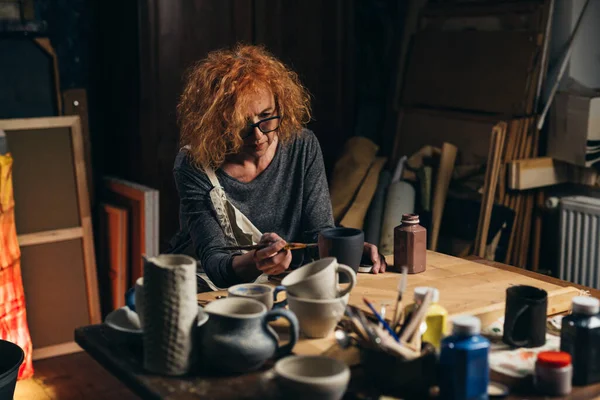 Atölyesinde çömlek oyan bir kadın.