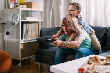 Anne ve oğlu evde video oyunu oynuyorlar.