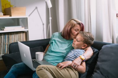 Bekar anne ve oğlu dizüstü bilgisayarlarını kullanarak evde vakit geçiriyorlar.