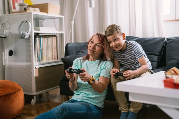 Beyaz tenli bekar anne oğluyla evde oyun oynuyor.