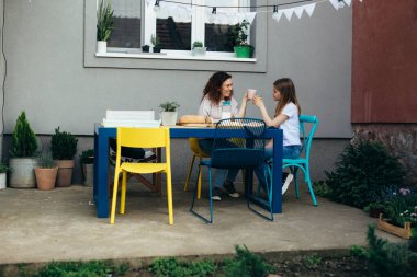 wide shoot of mother and daughter cheers while breakfast in their back yard