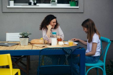 mother and daughter enjoying breakfast together at home in back yard