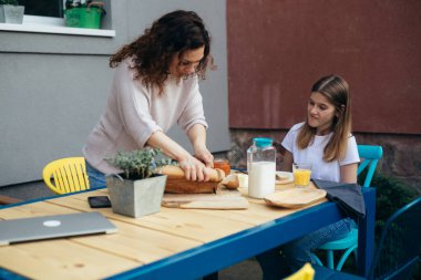 young caucasian mother and her daughter having breakfast outdoor in back yard