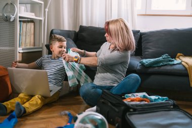 Anne ve oğul yaz tatili için valiz hazırlıyorlar.