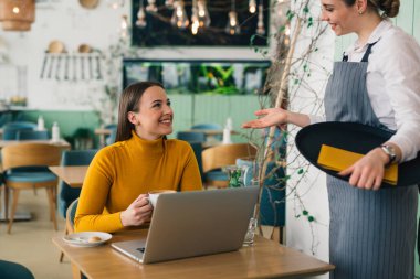 Kafkasyalı bir kadın restoranda bir garsonla konuşuyor, yemek sipariş ediyor.