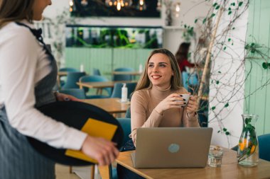Kafkasyalı bir kadın restoranda bir garsonla konuşuyor, yemek sipariş ediyor.