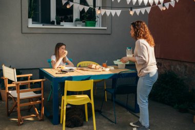 mother brings food to the table for breakfast in backyard