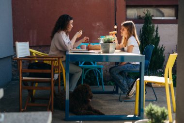 single mother and her daughter enjoying time together during breakfast in their backyard