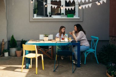 single mother and her daughter enjoying time together during breakfast in their backyard