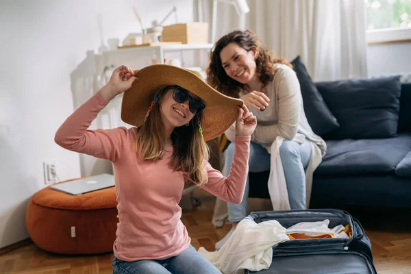 Young Teenager Girl Try Hat Sunglasses While Packing Her Mom — Stockfoto